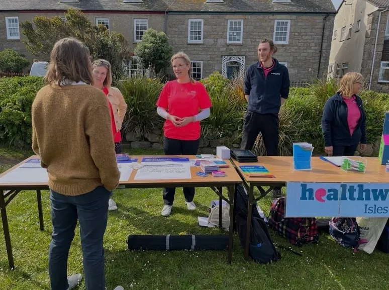 Photo depicting NHS colleagues speaking to people at the farmer’s market on the Isles of Scilly